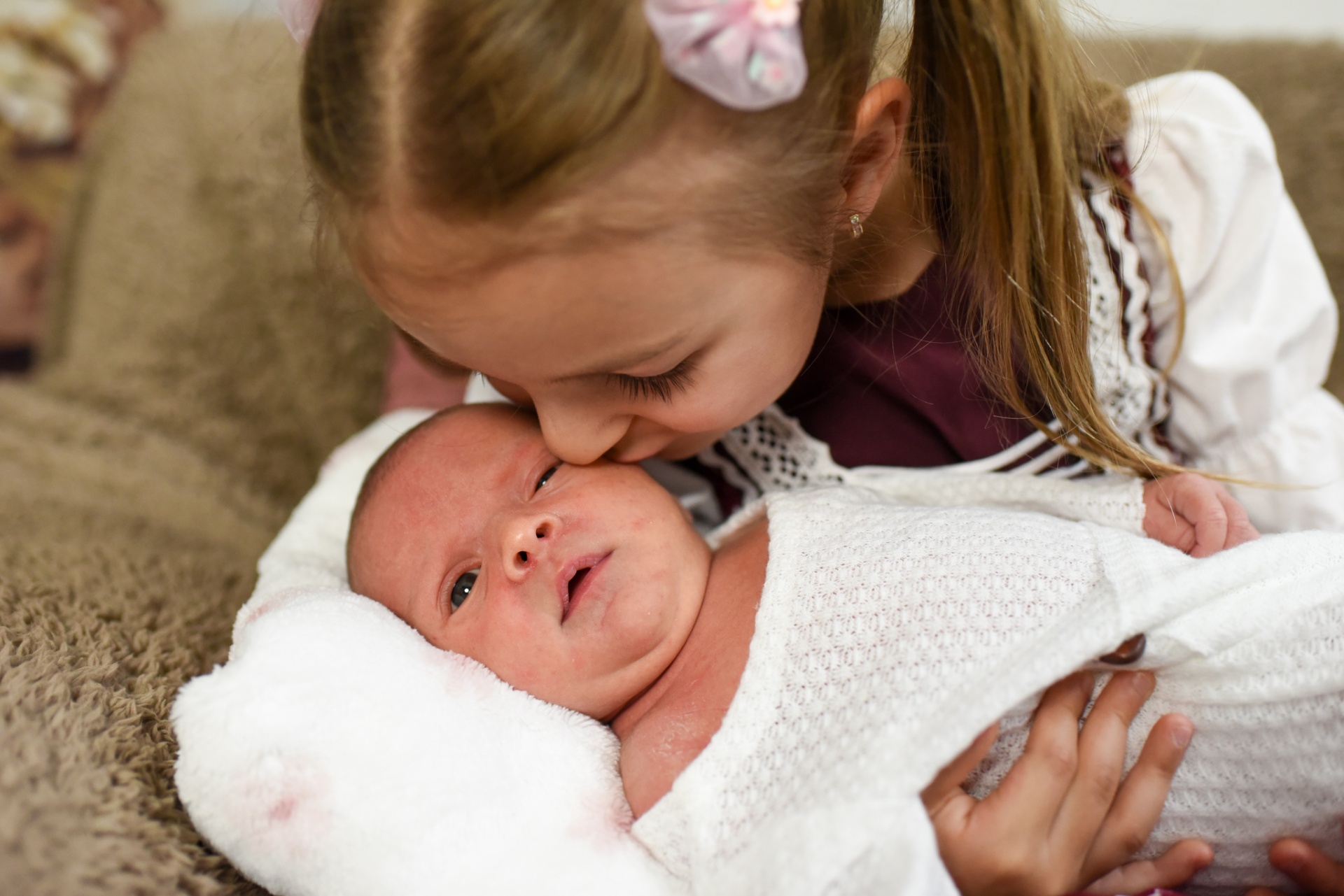 Schwester küsst Neugeborenes